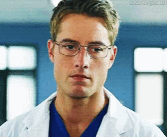 a close up of a man wearing glasses and a white lab coat