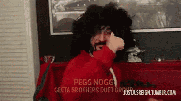 a man wearing a wig and a red shirt is giving a thumbs up sign .