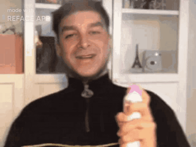 a man in a black jacket is holding a spray bottle and smiling