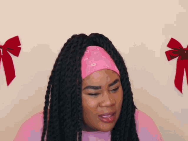 a woman with braids is wearing a pink headband and making a face .