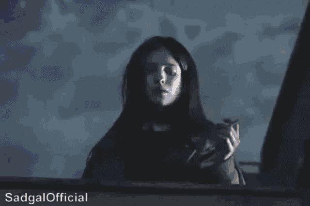 a woman in a dark room with the words sadgal official written below her