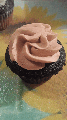 a close up of a cupcake with pink frosting on a table