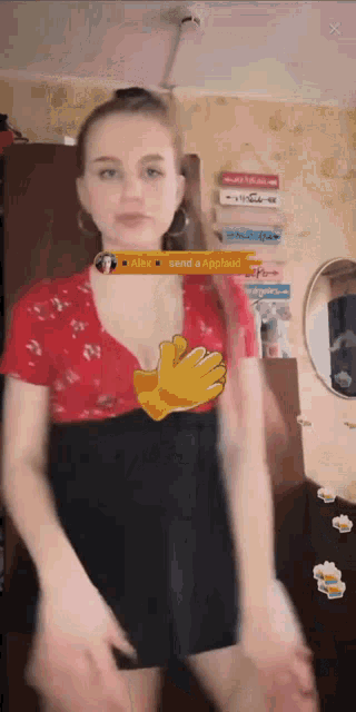 a woman in a red top and black skirt is dancing in a room .