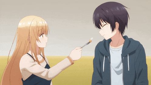 a girl is holding a brush to a man 's face