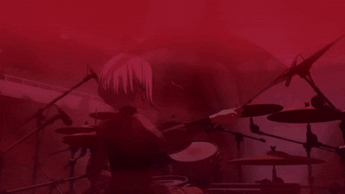 a woman is playing drums in a dark room with a red background .