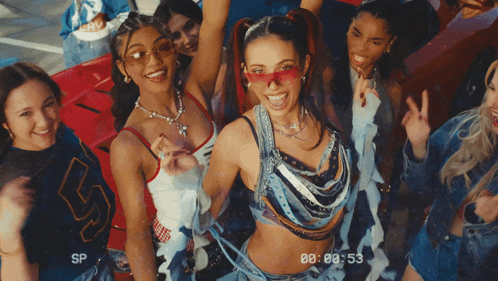 a group of young women are standing in front of a red car and the time is 00:00:53