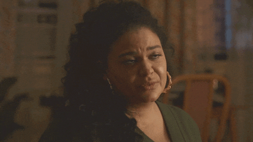 a woman with curly hair is wearing a green shirt