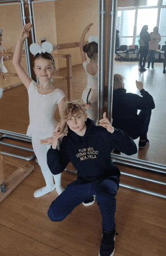 a boy wearing a black hoodie that says ' plus des sens ' on it poses next to a girl