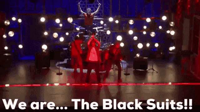a group of people standing on a stage with the words we are the black suits