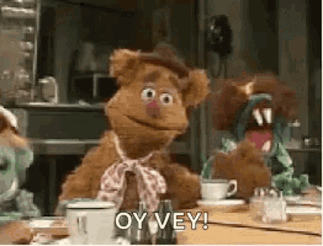 a group of muppets are sitting at a table with cups and saucers .