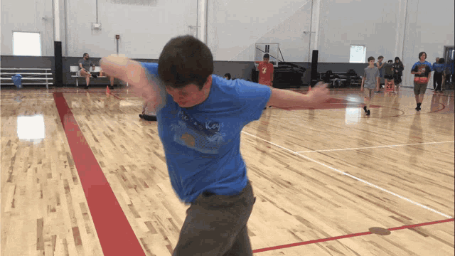 a boy wearing a blue shirt that says ' hawaii ' on it is throwing a ball