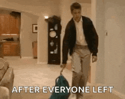a man is carrying a suitcase in a living room and says after everyone left