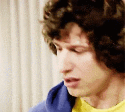 a man with curly hair is wearing a yellow shirt and a blue jacket .