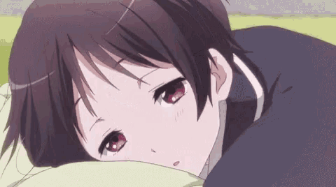 a girl is laying on a bed with her head on a pillow and looking at the camera .