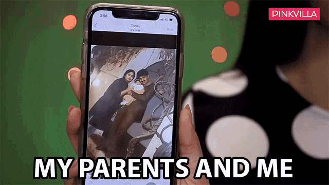 a woman is holding a cell phone with a picture of her parents and a baby