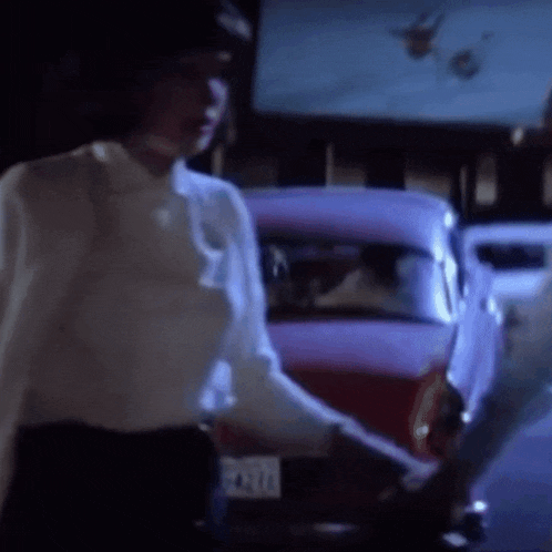 a woman in a white shirt is standing in front of a car with a license plate that says ' a ' on it