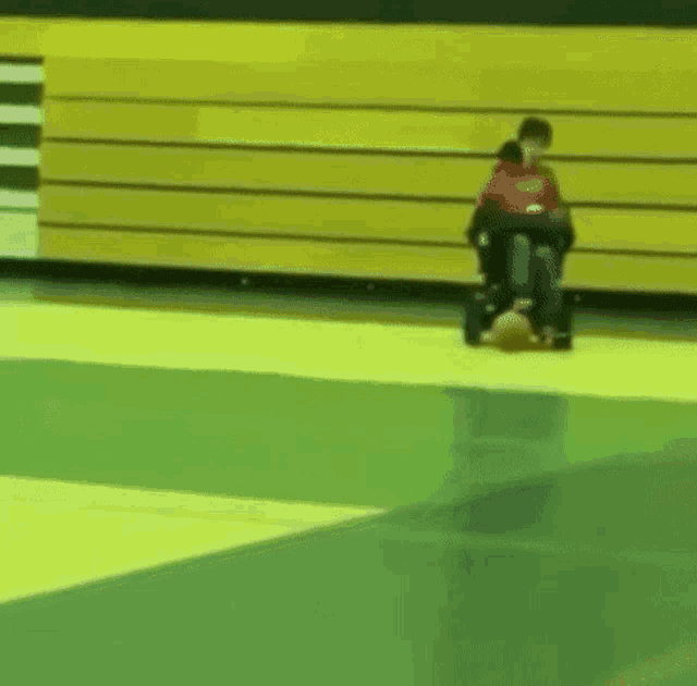 a person in a wheelchair is riding a skateboard on a green and yellow floor .