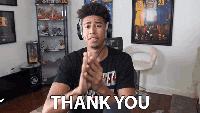 a man wearing headphones says thank you in front of a picture of a basketball player