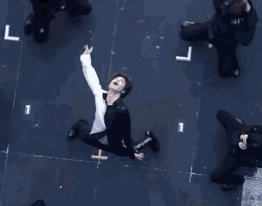 a man in a white shirt and black pants is dancing on a stage with a number 1 in the background