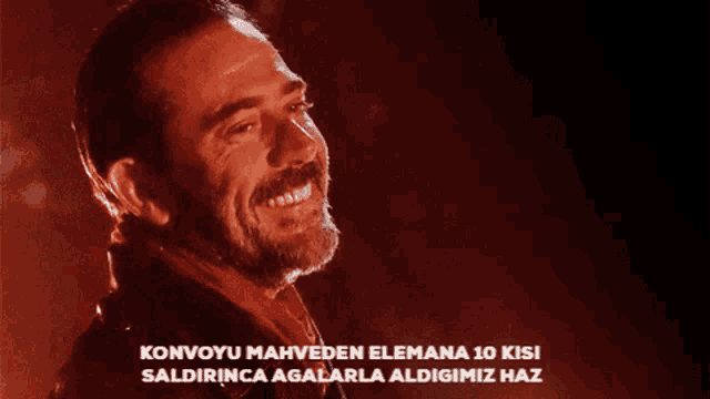 a man with a beard is smiling in front of a red background with the words konvoyu mahveden elemana 10 kisi