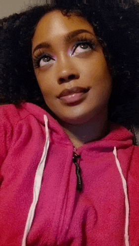 a woman wearing a pink hoodie is looking up at the camera .