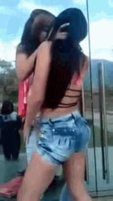 a couple of women standing next to each other with one wearing shorts
