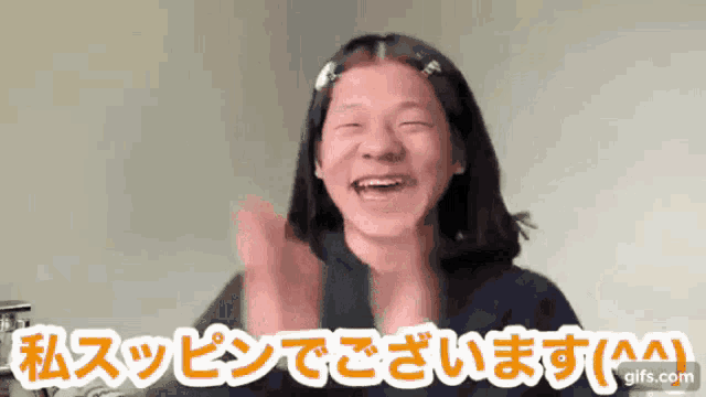a woman is smiling and clapping her hands in a video with japanese writing .