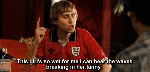 a man in a red shirt is talking to another man in a bar .