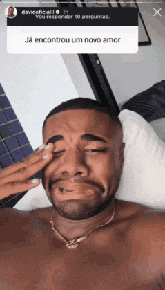a shirtless man is laying in bed with his eyes closed and his hand on his forehead ..