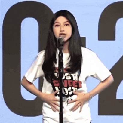 a woman stands in front of a microphone wearing a shirt that says just sweet ost