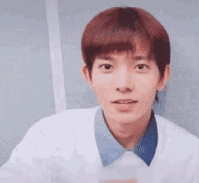 a close up of a young man wearing a white sweater and a blue shirt .