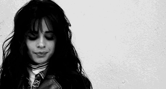 a black and white photo of a woman with long hair wearing a leather jacket and a striped shirt .