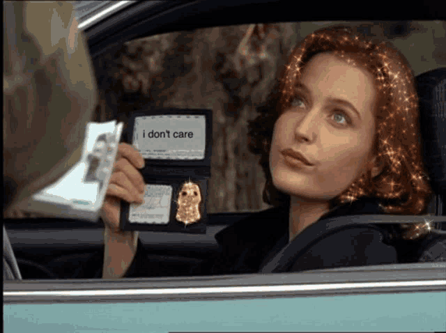 a woman in a car holds up a badge that says i don 't care