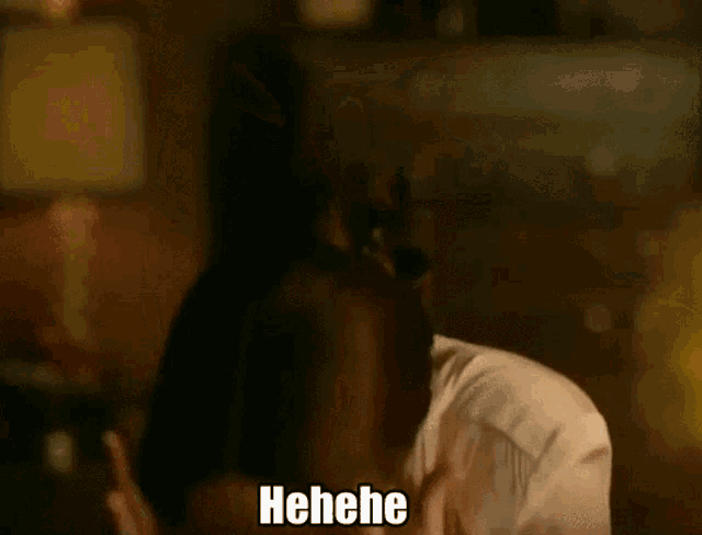 a woman is laughing while talking on a cell phone and the word henehe is on the bottom of her face .