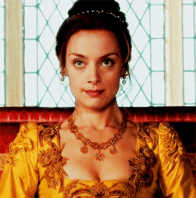 a woman in a yellow dress and gold necklace