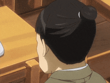 a person with a bun on their head is sitting in a classroom