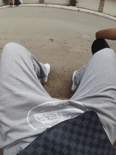 a person wearing grey sweatpants and a louis vuitton wallet