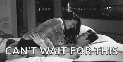 a man and a woman are laying on a bed kissing .
