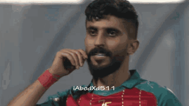 a man with a beard wearing a green and red shirt with the number 25 on it