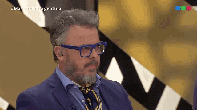 a man with glasses and a beard is appearing on a television show called masterchef argentina