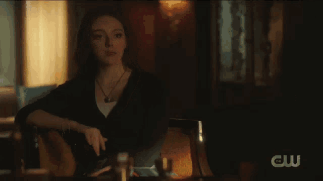 a woman is sitting in a chair in a dark room with a necklace on her neck .