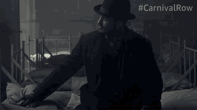 a man in a suit and top hat stands in front of a row of beds with #carnivalrow written on the bottom