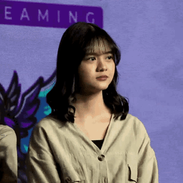 a woman stands in front of a purple sign that says eaming