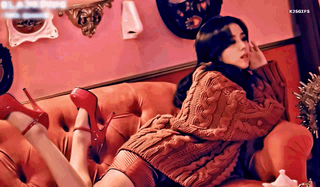 a woman in a red sweater and red heels laying on a couch