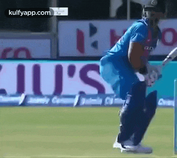 a cricket player is standing on a field with a bat .