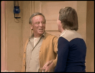 two men are standing next to each other in front of a door .