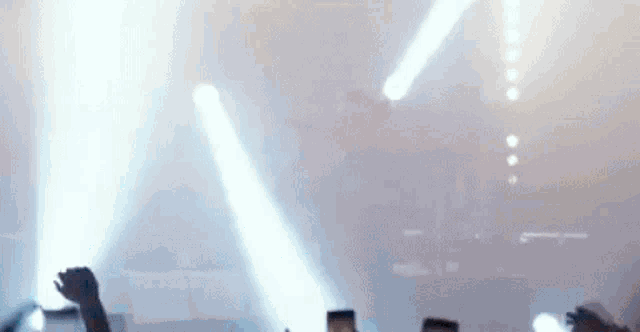 a group of people are standing in front of a stage with their hands in the air at a concert .