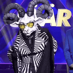 a man in a blue suit is standing next to a goat wearing sunglasses and a striped jacket .