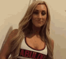 a woman with long blonde hair is wearing a white tank top that says abuild on it .