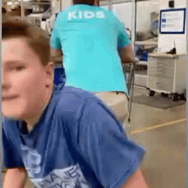 a man wearing a blue shirt that says kids is standing next to a boy .